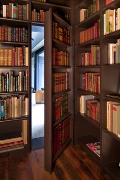 an open bookcase with many books on it in a room filled with wooden floors