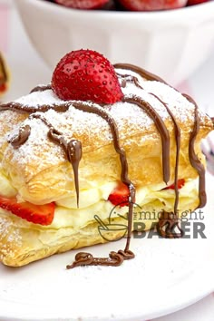 a pastry with strawberries and chocolate drizzled on top is sitting on a plate