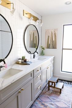 a bathroom with two sinks, mirrors and rugs on the floor in front of windows