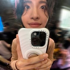 a woman taking a selfie with her cell phone in front of her face and blurry background