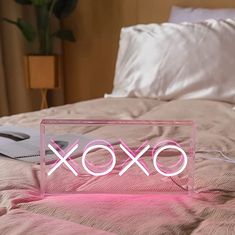 an xoxo neon sign sitting on top of a bed