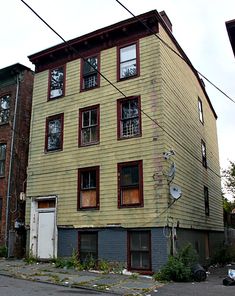 an apartment building with boarded up windows and no doors on the side of the street