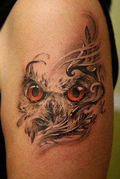 an owl tattoo with orange eyes on the arm