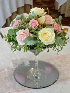 a glass vase filled with pink and white flowers on top of a table covered in tables cloths