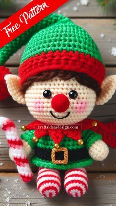 a crocheted christmas elf doll sitting on top of a wooden table next to candy cane