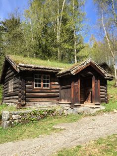 an old log cabin with grass on the roof