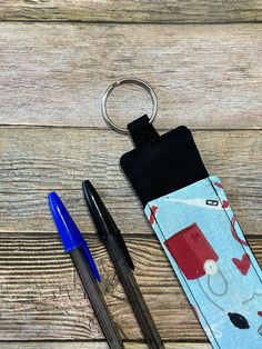 two pens and a keychain sitting on top of a wooden table