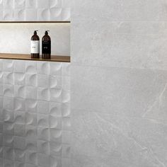 a white tiled bathroom with two bottles on the shelf