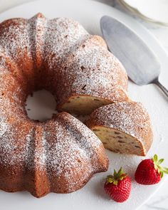 a bundt cake with powdered sugar on top and two strawberries next to it