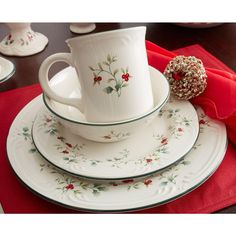 a stack of cups and saucers sitting on top of a red table cloth next to a donut