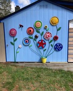 a blue shed with flowers painted on it's side and a potted plant in the foreground