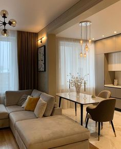 a living room filled with furniture next to a dining room table and window covered in curtains