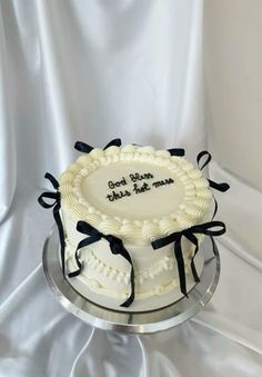 a white cake with black ribbon on top is sitting on a silver platter that says, god loves you so much