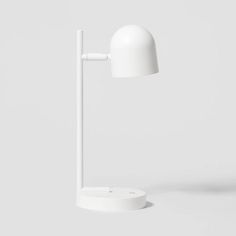 a white table lamp on top of a white surface next to a black and white object