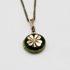 "A tiny brass locket opens to hold two photographs that we place for you.  This piece features an antiqued brass four leaf clover against an emerald green enamel. ~1/2\" ~Photos with one or two close together subjects work best *Made to order.  Please allow 5-10 business days for production." Brass Locket Necklace With Charms For Keepsake, Green Locket Jewelry, Green Medallion Locket Jewelry, Antique Green Locket Jewelry, Antique Brass Locket Necklace With Charms, Vintage Brass Jewelry For Good Luck, Antique Green Locket Necklace, Vintage Good Luck Locket Jewelry, Vintage Green Locket Necklace