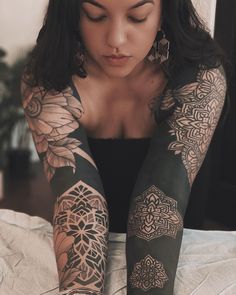 a woman sitting on top of a bed with tattoos on her arms and leggings