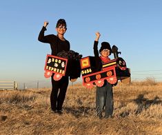 two people standing in a field holding up signs