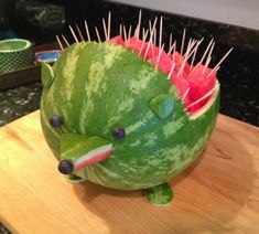 a watermelon shaped like a fish with spikes on it's head sitting on a cutting board