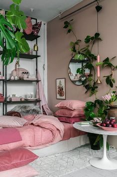 a bedroom with pink bedding and green plants on the wall, along with two round mirrors