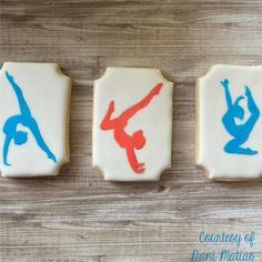 three decorated cookies with blue and red icing on top of a wooden table next to each other