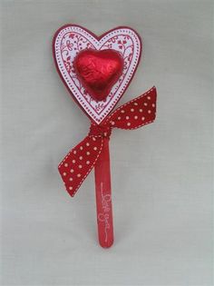 a heart shaped lollipop on a stick with a red ribbon tied around it