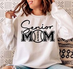 a woman sitting on a couch wearing a white shirt with the word senior mom printed on it