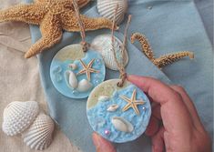 two handmade seashells and starfish ornaments on a blue cloth with shells