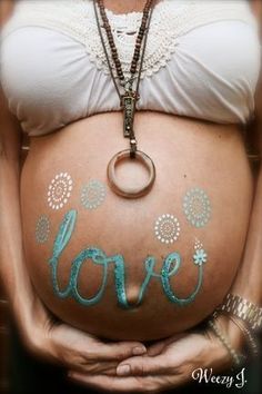 a pregnant woman holding her belly with the word love painted on it