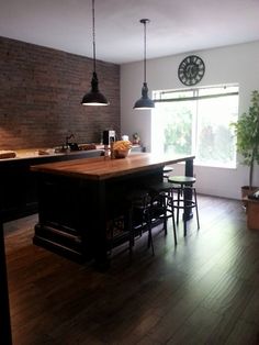 a kitchen with wooden floors and an island in front of a clock mounted on the wall