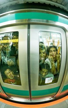 people are taking pictures in the reflection of their mirrors as they ride on a subway train