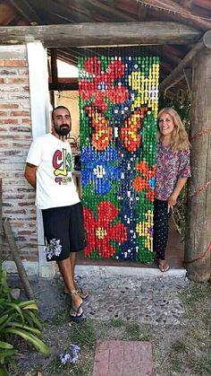 a man and woman standing in front of a door made out of plastic bottle caps