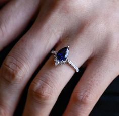 a woman's hand with a diamond and blue sapphire ring on her left hand