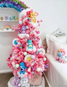 there is a pink christmas tree decorated with stuffed animals and rainbows in the corner