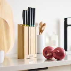 an assortment of kitchen utensils in a wooden holder on a white countertop