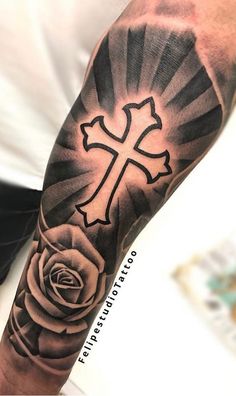 a man with a cross and rose tattoo on his arm