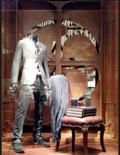 a mannequin dressed in a white suit and tie next to a table with books