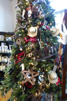 a christmas tree decorated with hats and other holiday decorations in a store display area,