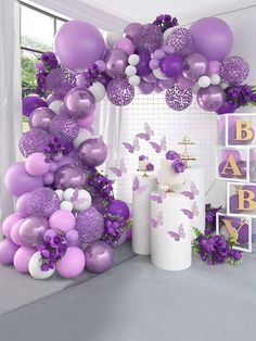 purple and white balloons are hanging from the ceiling in front of a wall with pictures on it