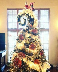 a decorated christmas tree in front of a window with the letter g on it's top