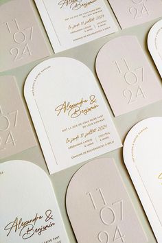 the wedding stationery is laid out on top of each other, with gold lettering