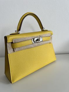 a yellow handbag sitting on top of a table next to a white wall,