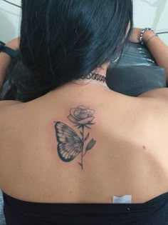 a woman with a butterfly and rose tattoo on her upper back shoulder is looking at the camera