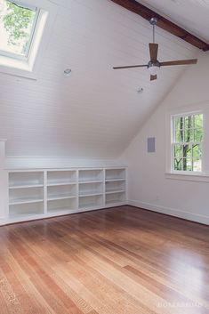 an empty room with wooden floors and white walls, has a ceiling fan in the corner