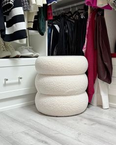 a closet filled with lots of clothes next to a white cabinet and drawers on top of wooden flooring