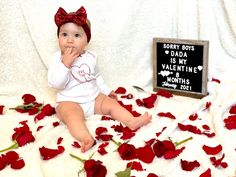 a baby sitting on a blanket with roses around it and a sign that says sorry boys is my valentine