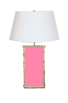 a pink lamp with a white shade on the bottom and a gold frame around it