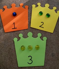 three pieces of paper with numbers and crowns on them sitting on the floor next to each other