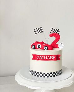 a birthday cake decorated with a racing car and number two on top is sitting on a pedestal