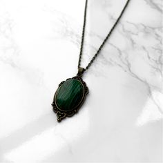 Malachite Pendant Necklace | Antique Silver or Gold | 24" Chain Clairvoyance + Transformation + Road Opener + Emotional Balance Carry your intentions wherever you go with a handmade Malachite pendant necklace. Each pendant is custom made with an antique gold or silver filigree base and comes with an 24" chain with lobster clasp fastening. Malachite is often referred to as the Stone of Transformation. It was a stone favored by the ancient Greeks and Egyptians for its protective and healing properties. Malachite is a heart chakra stone that works by removing whatever is blocking growth in your life and opening your heart and mind to new possibilities. Whether you are ready to take a leap of faith or feeling stagnant in life, this stone will give you clarity of purpose and the courage to move Green Oval Pendant Necklace Engraved, Green Oval Pendant Necklace With Engraving, Antique Handmade Necklace For Meditation, Vintage Brass Necklaces For Meditation, Green Brass Spiritual Necklaces, Spiritual Green Brass Necklaces, Oval Malachite Necklace As Gift, Vintage Malachite Jewelry For Gifts, Vintage Malachite Jewelry Gift