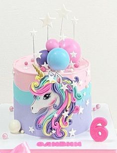 a birthday cake decorated with an unicorn and balloons